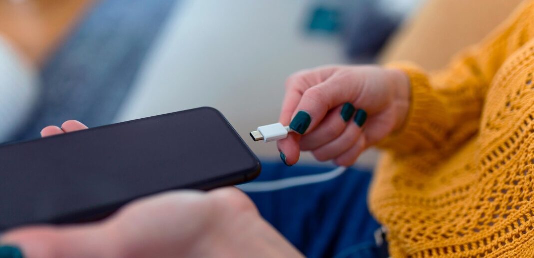 Persona cargando un teléfono celular conectado a un tomacorriente